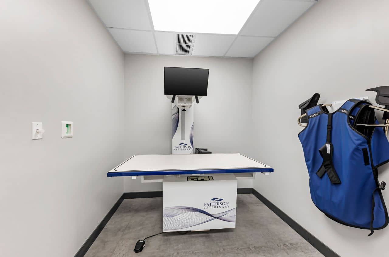 An empty x-ray room with protective vest hung on wall